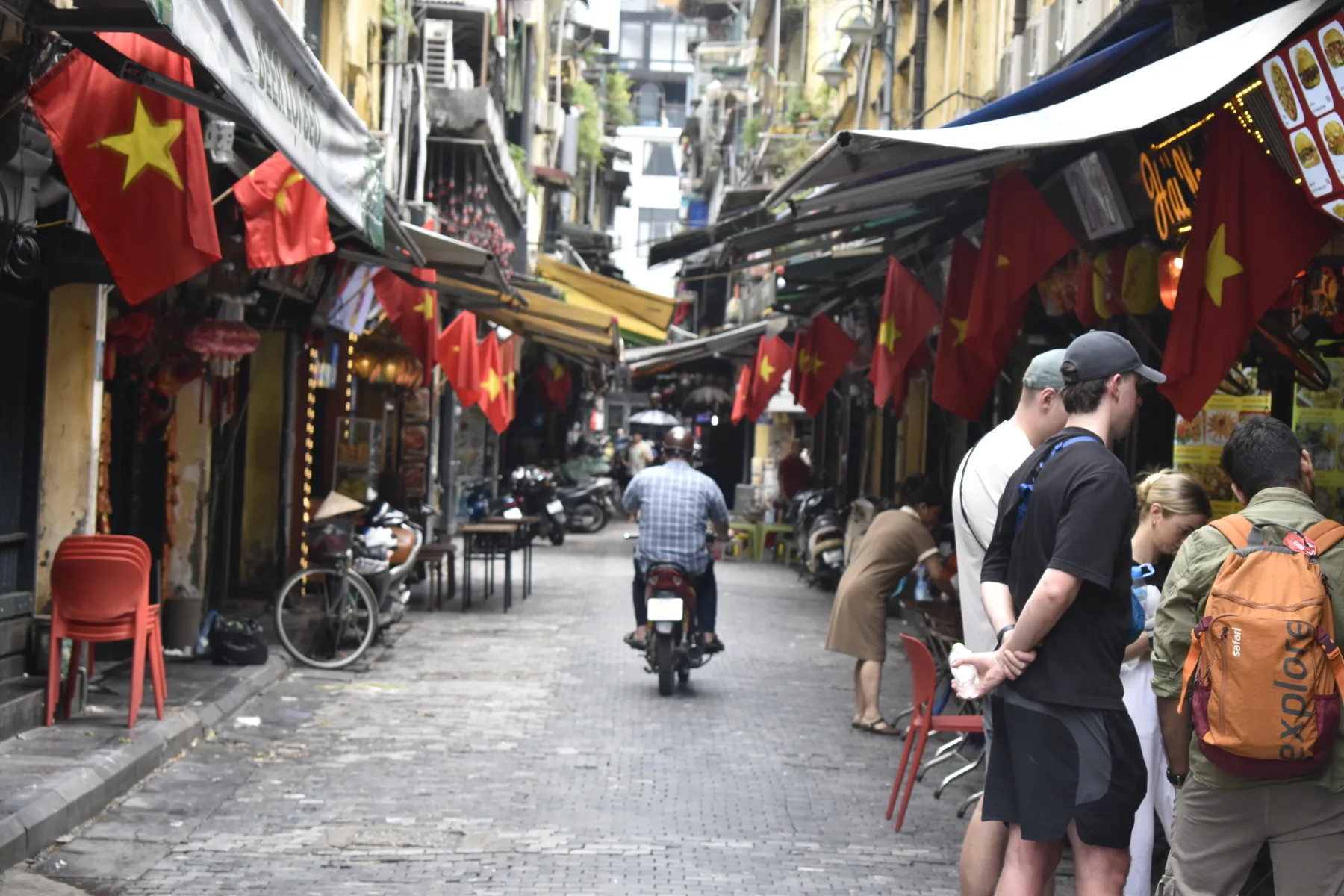 A narrow street in Vietnam lined with flags and food stalls